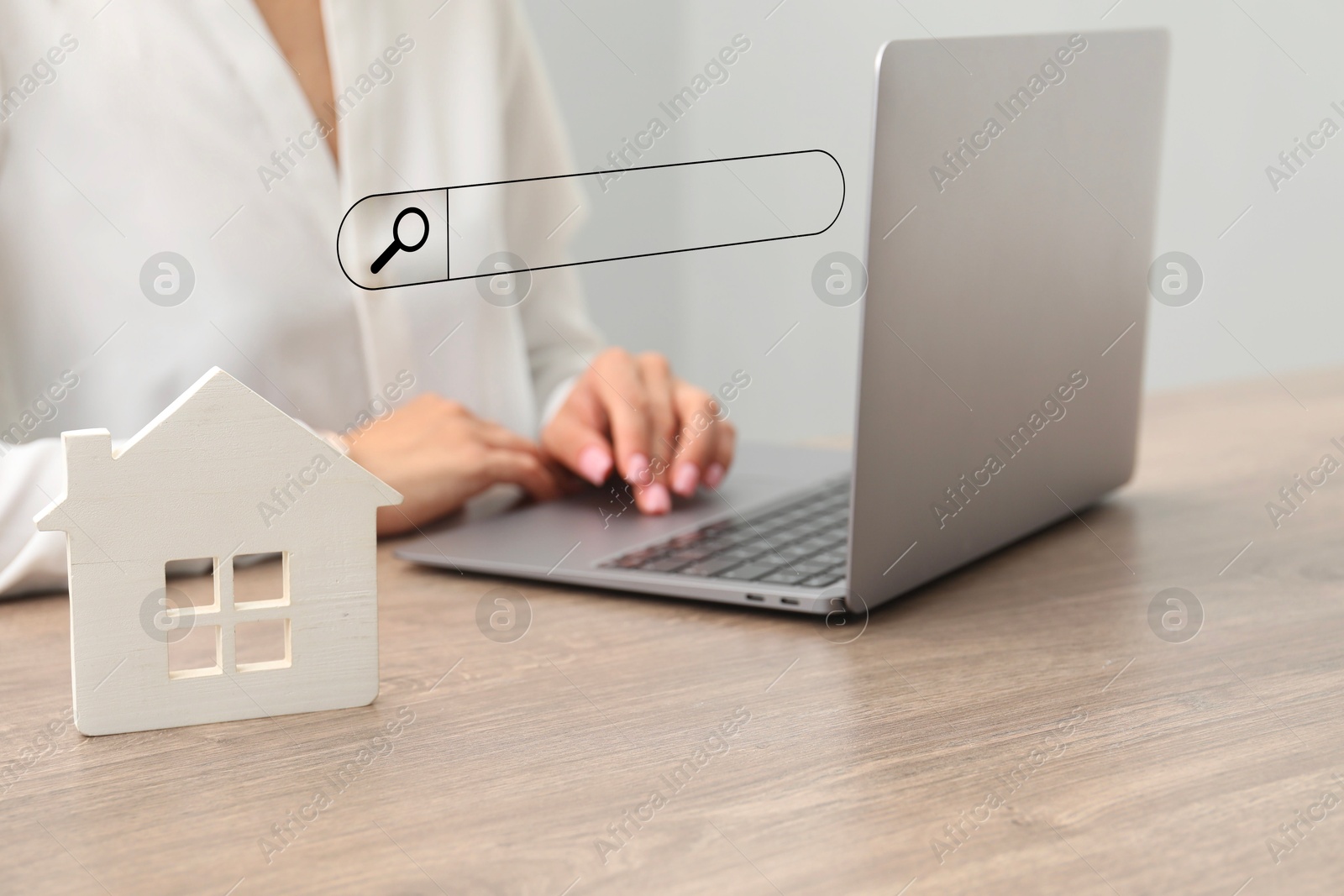 Image of Searching for housing online. Real estate agent using laptop at table with house model, closeup. Search bar above computer