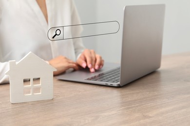Image of Searching for housing online. Real estate agent using laptop at table with house model, closeup. Search bar above computer