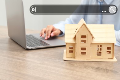 Image of Searching for housing online. Real estate agent using laptop at table, closeup. Search bar above house model