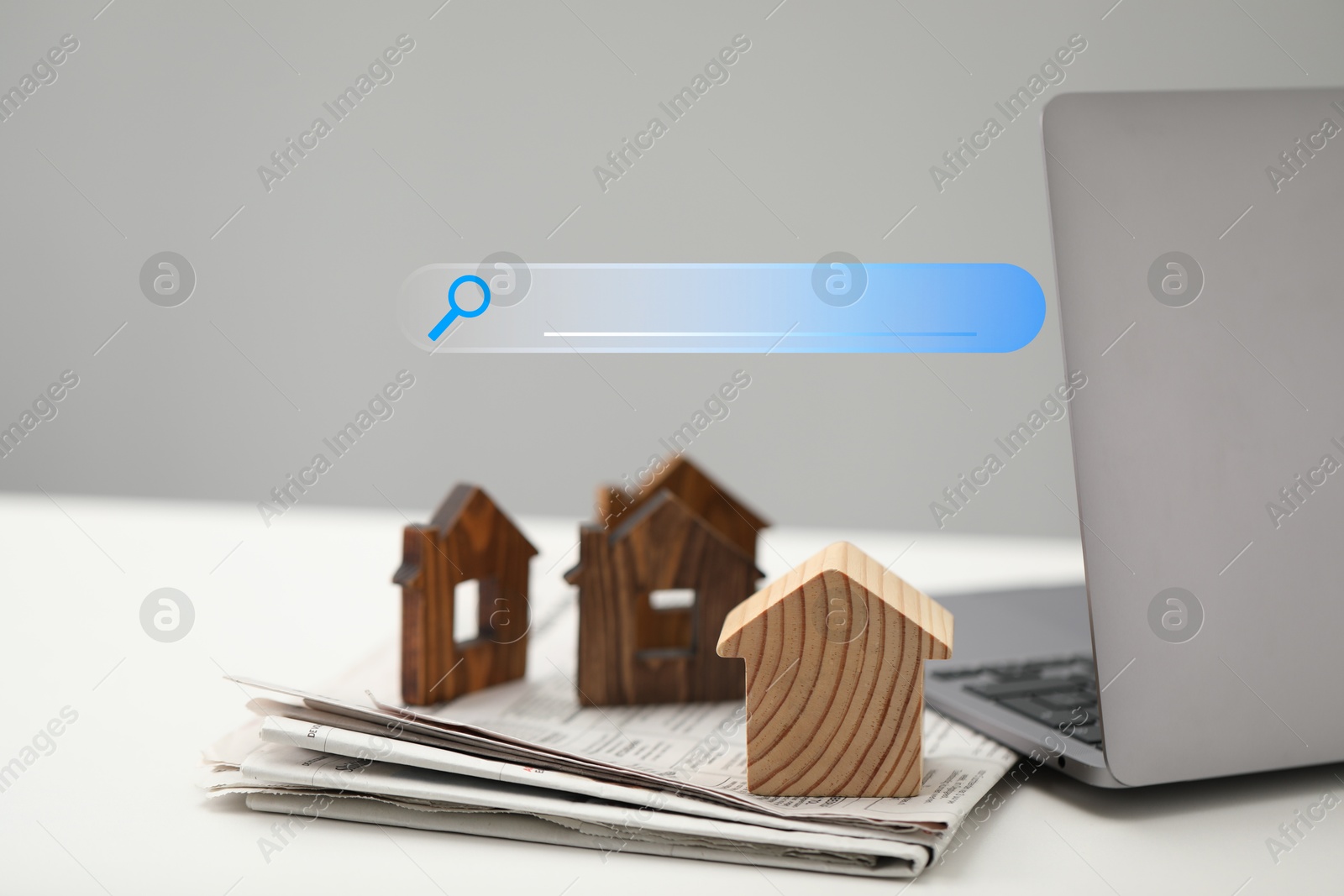 Searching for housing online. Laptop and house models on table. Search bar near computer Image of Searching for housing online. Laptop and house models on table. Search bar near computer