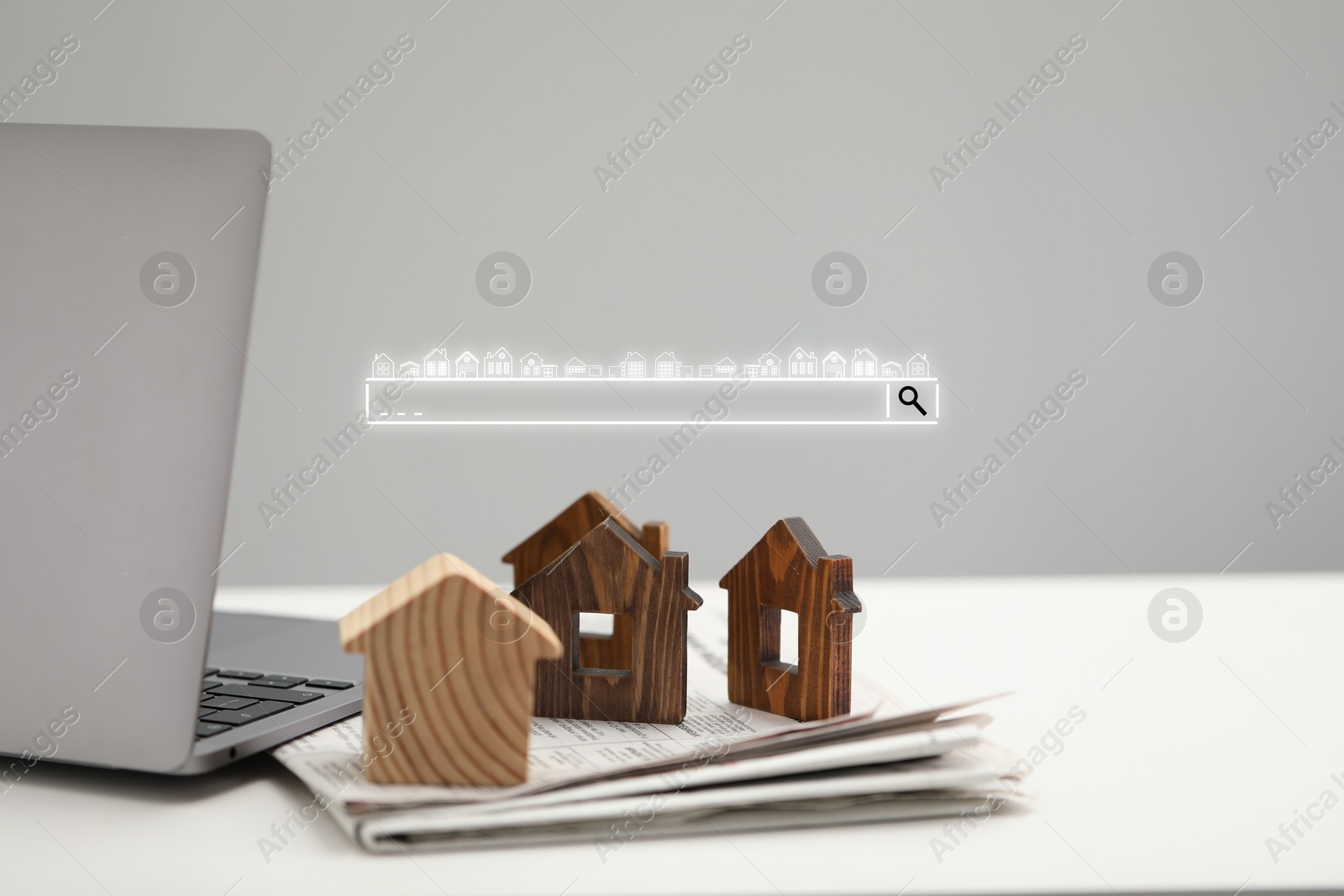 Searching for housing online. Laptop and house models on table. Search bar near computer Image of Searching for housing online. Laptop and house models on table. Search bar near computer