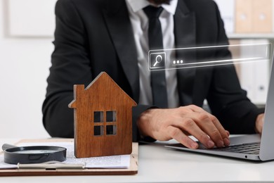 Image of Searching for housing online. Real estate agent using laptop at table with magnifying glass and house model, closeup. Search bar above computer