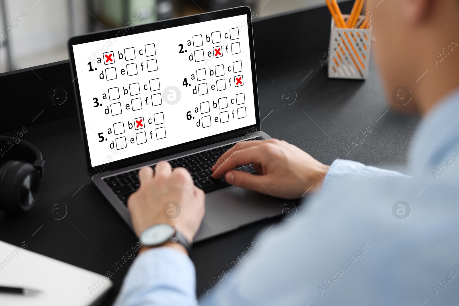 Man passing online test on laptop at table, closeup Image of Man passing online test on laptop at table, closeup
