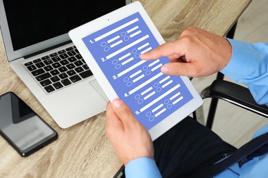 Image of Man passing online test on tablet computer at table, closeup