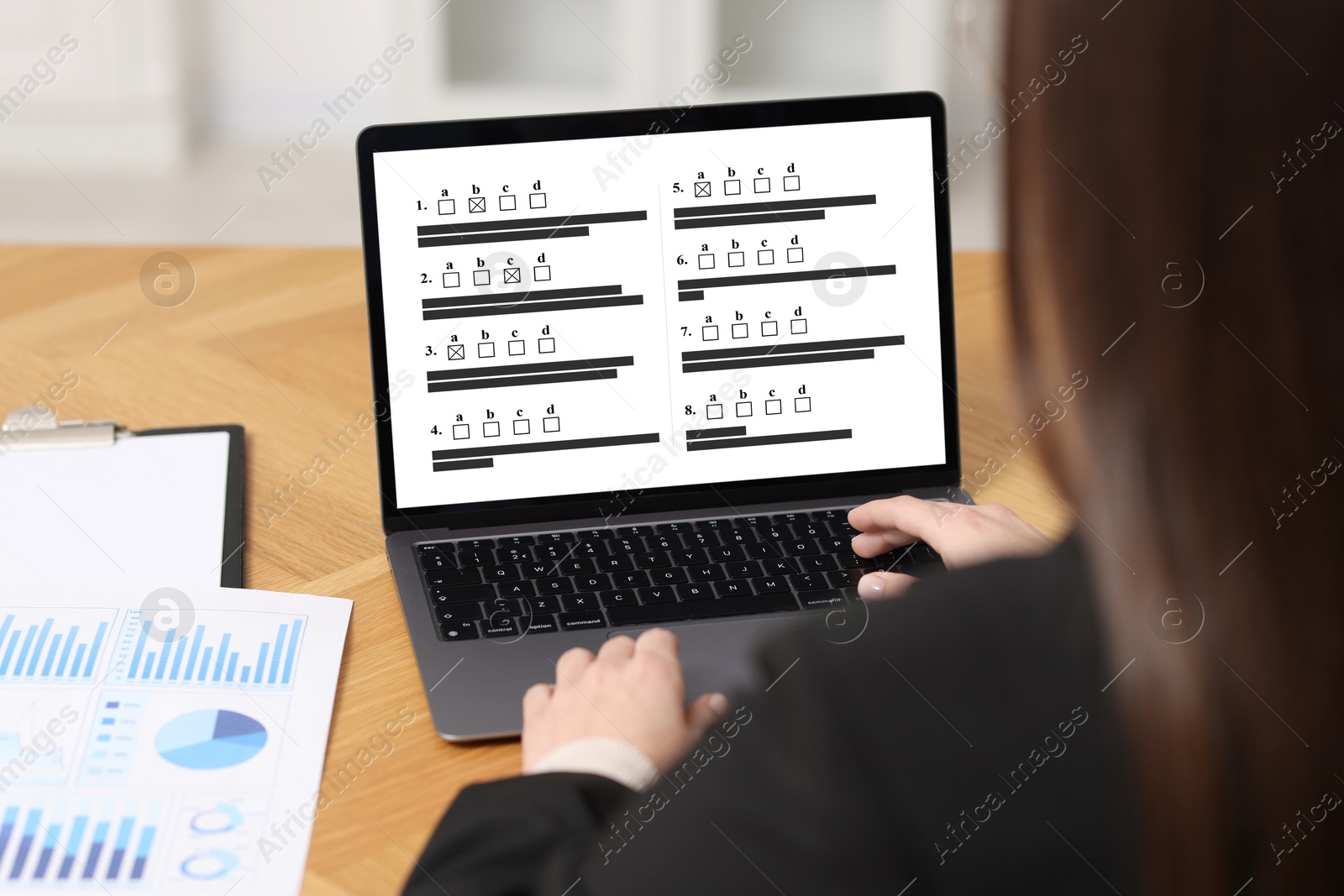Woman passing online test on laptop at table, closeup Image of Woman passing online test on laptop at table, closeup