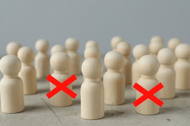 Image of Dismissal. Two human figures with red crosses among others on grey table