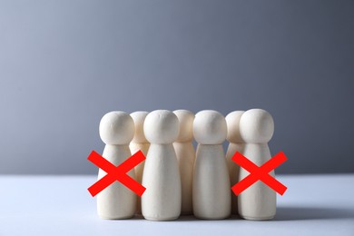 Image of Dismissal. Two human figures with red crosses among others on grey table