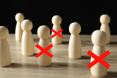 Image of Dismissal. Three human figures with red crosses among others on wooden table
