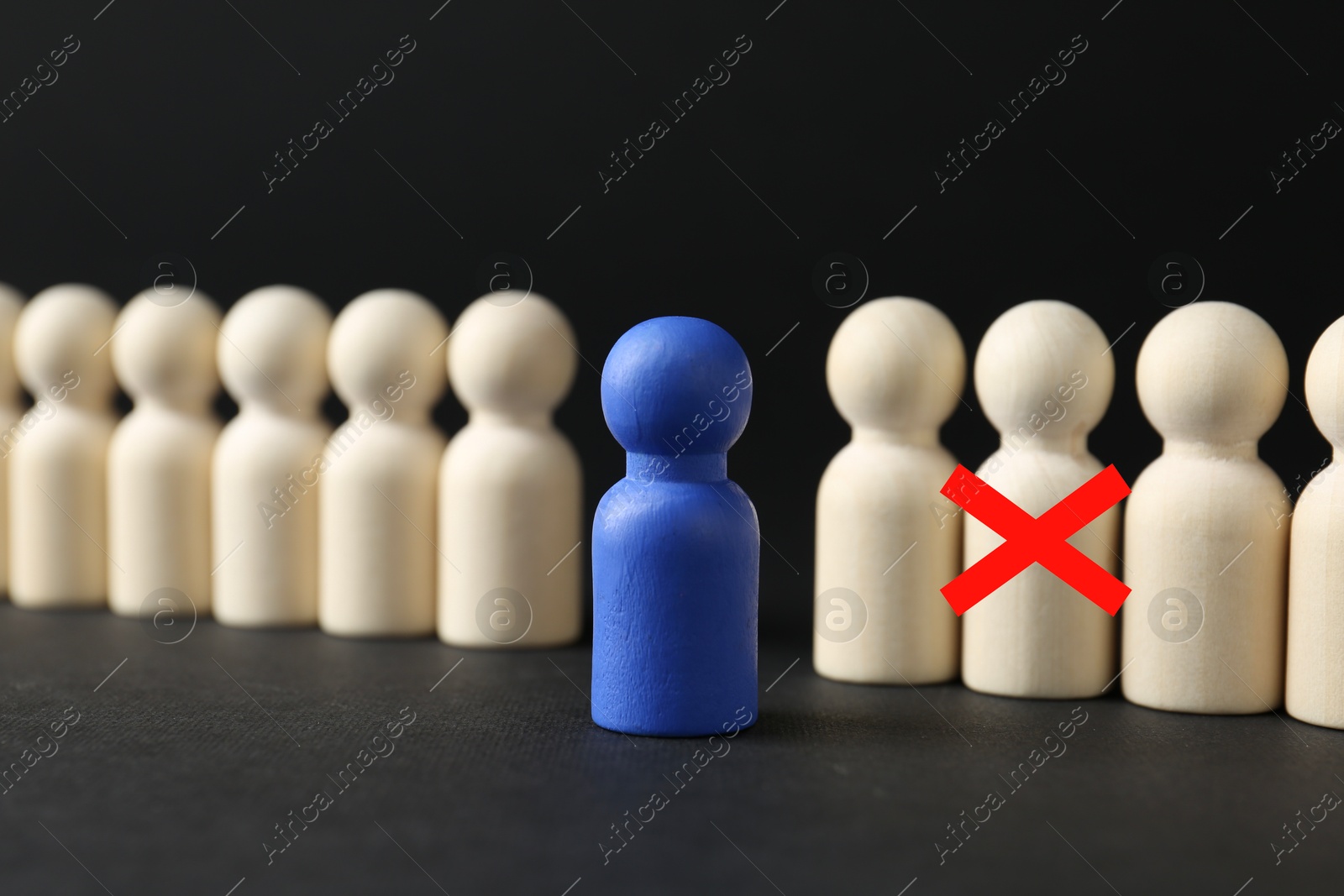 Dismissal. One human figure with red cross among others on black table. Blue figure - boss or HR manager Image of Dismissal. One human figure with red cross among others on black table. Blue figure - boss or HR manager