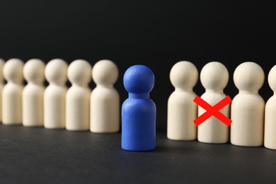 Image of Dismissal. One human figure with red cross among others on black table. Blue figure - boss or HR manager