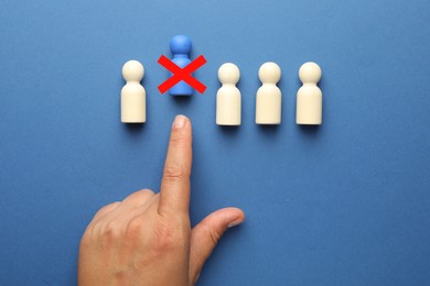 Image of Dismissal. Woman throwing human figure with red cross away on blue background, top view