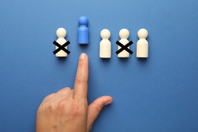Image of Dismissal. Two human figures with black crosses on blue background, top view. Woman throwing another one, closeup