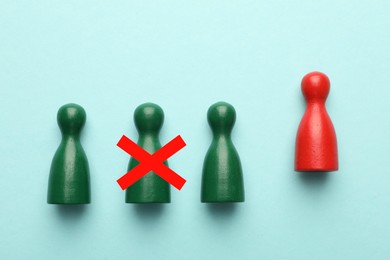 Image of Dismissal. One green human figure with red cross among others on light blue background, top view