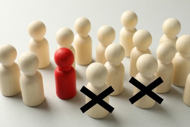 Image of Dismissal. Two human figures with black crosses among others on white table