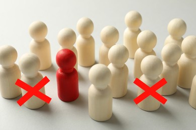 Image of Dismissal. Two human figures with red crosses among others on white table