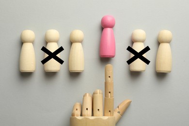 Image of Dismissal. Two human figures with black crosses on grey background, top view. Mannequin hand throwing another one away