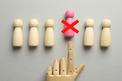 Image of Dismissal. Mannequin hand throwing pink human figure with red cross away on grey background, top view