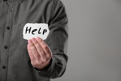 Image of Man holding paper with word Help against grey background, closeup