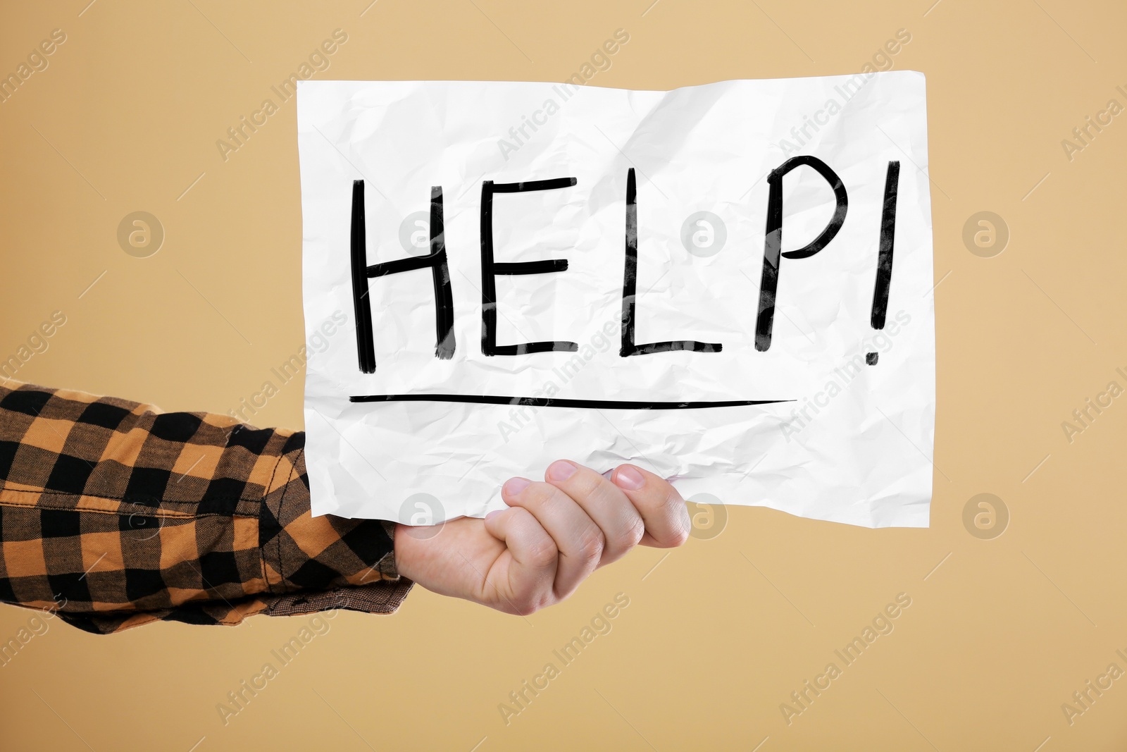 Man holding paper with word Help against pale orange background, closeup Image of Man holding paper with word Help against pale orange background, closeup