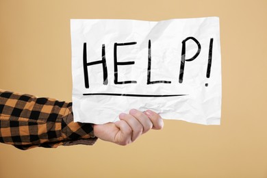 Image of Man holding paper with word Help against pale orange background, closeup