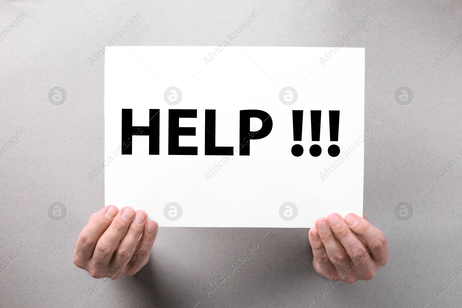 Asking or offering help. Man holding paper with word through holes in grey paper, closeup Image of Asking or offering help. Man holding paper with word through holes in grey paper, closeup