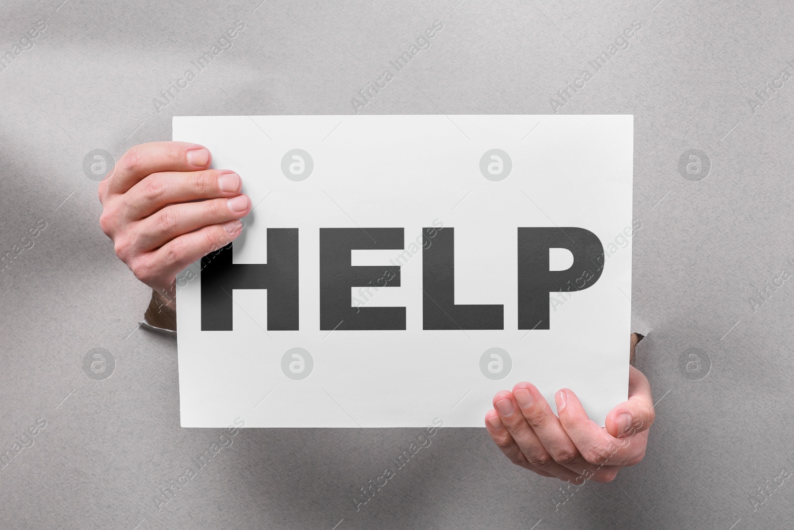 Asking or offering help. Man holding paper with word through holes in grey paper, closeup Image of Asking or offering help. Man holding paper with word through holes in grey paper, closeup