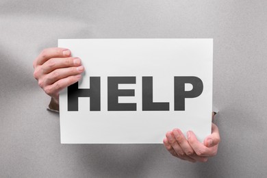 Image of Asking or offering help. Man holding paper with word through holes in grey paper, closeup