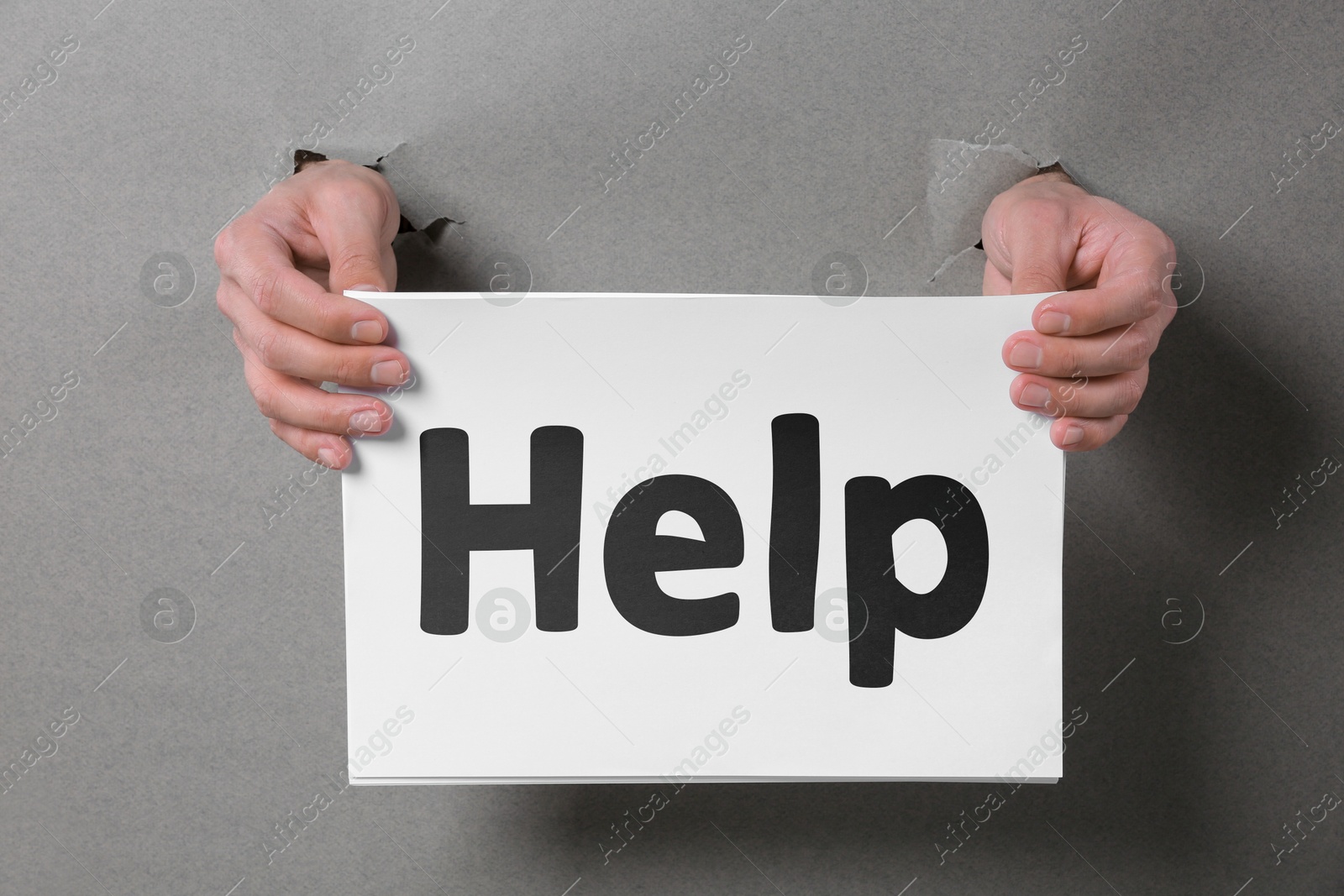 Image of Asking or offering help. Man holding paper with word through holes in grey paper, closeup