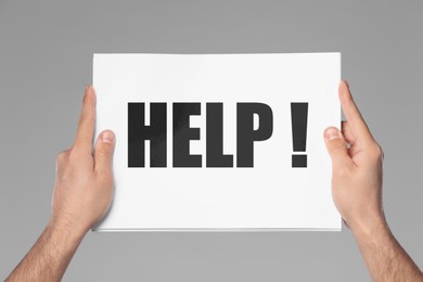 Image of Asking or offering help. Man holding paper with word against grey background, closeup