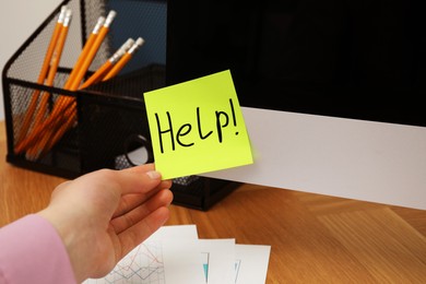 Image of Woman taking paper note with word Help from monitor at workplace, closeup