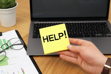 Image of Man holding paper notes with word Help at workplace, closeup