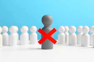 Image of Dismissal. One grey human figure with red cross among others on white table