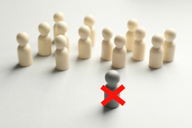 Image of Dismissal. One grey human figure with red cross among others on white table