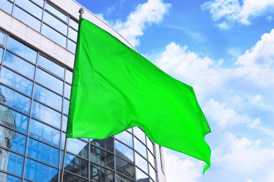 Image of Bright green flag waving against building outdoors