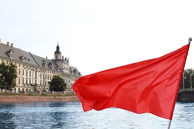 Image of Bright red flag waving against building outdoors