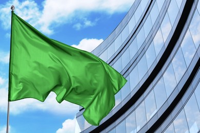 Image of Bright green flag waving against building outdoors