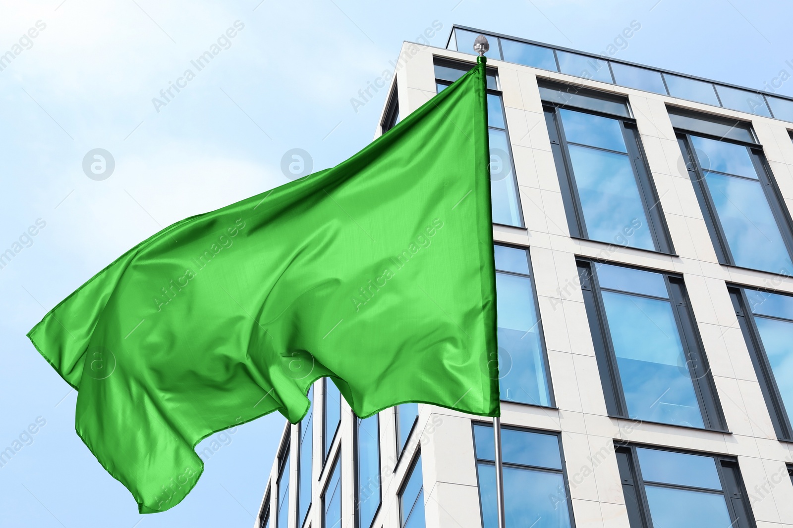 Bright green flag waving against building outdoors Image of Bright green flag waving against building outdoors