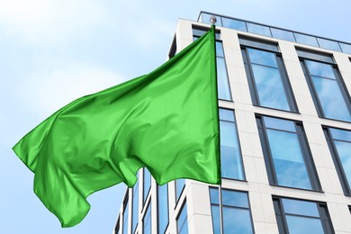 Image of Bright green flag waving against building outdoors