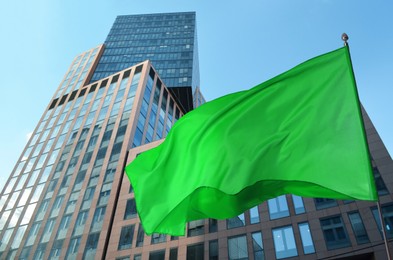 Image of Bright green flag waving against building outdoors
