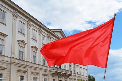 Image of Bright red flag waving against building outdoors