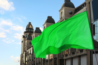 Image of Bright green flag waving against building outdoors