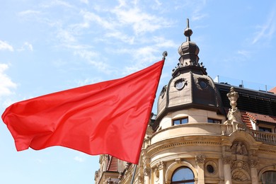 Image of Bright red flag waving against building outdoors