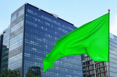 Image of Bright green flag waving against building outdoors