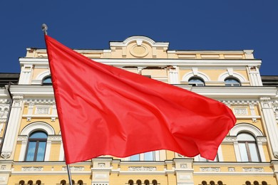Image of Bright red flag waving against building outdoors