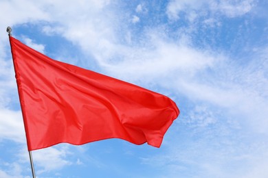 Image of Red flag waving against blue sky outdoors