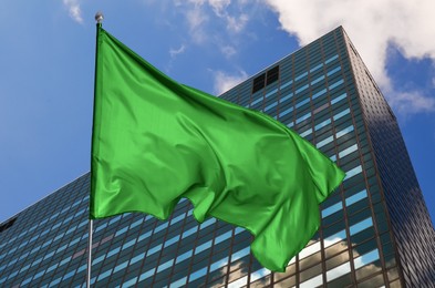 Image of Bright green flag waving against building outdoors