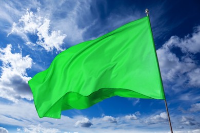 Image of Green flag waving against blue sky outdoors