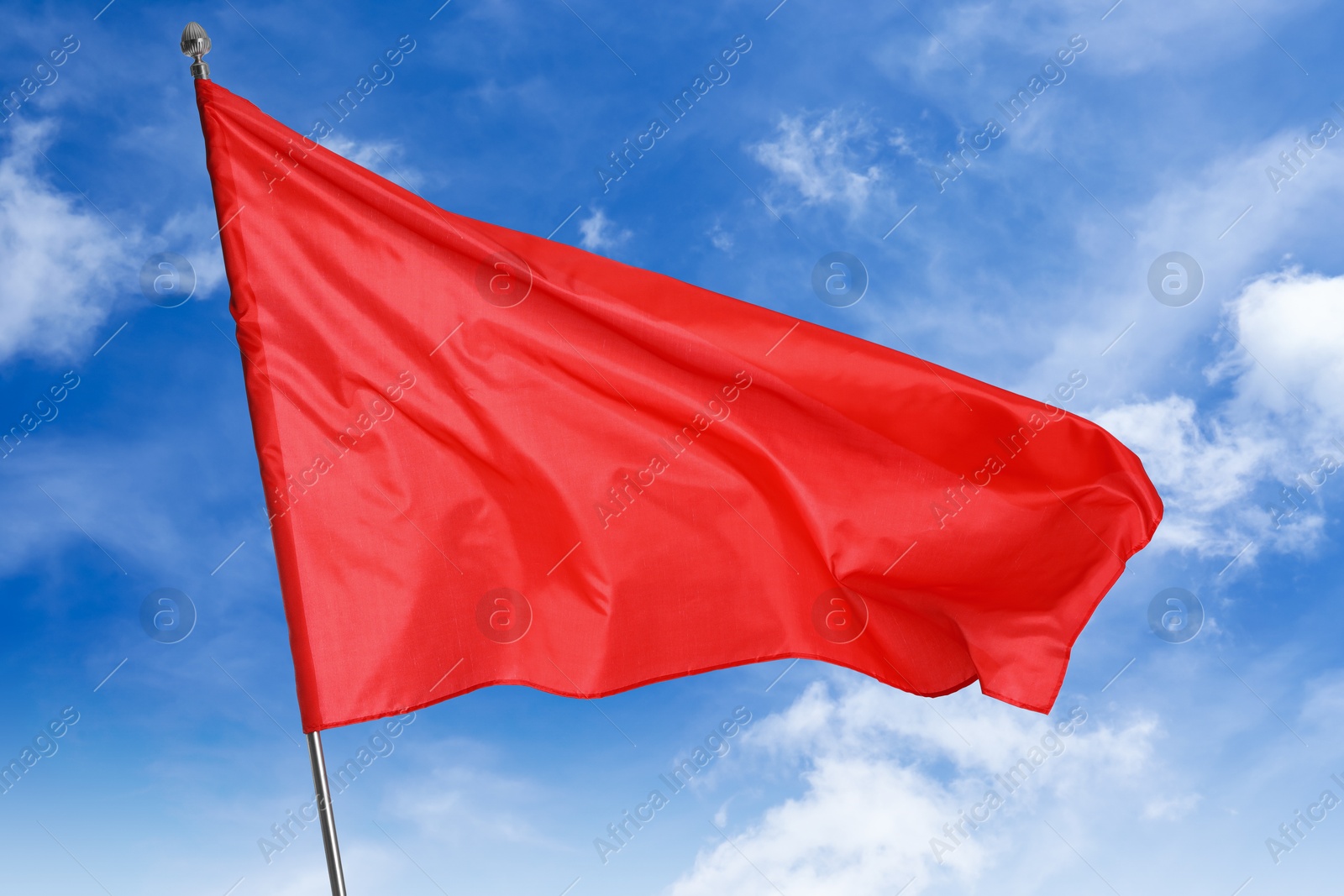Red flag waving against blue sky outdoors Image of Red flag waving against blue sky outdoors
