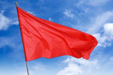 Image of Red flag waving against blue sky outdoors