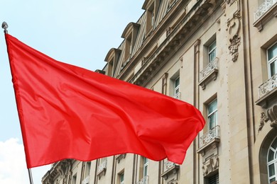 Image of Bright red flag waving against building outdoors